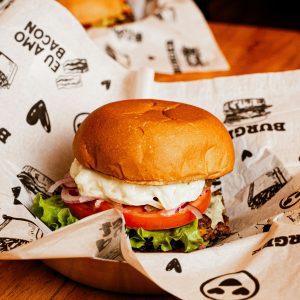 Fresh cheeseburger with lettuce, onion, tomato, and cheese served on parchment paper.